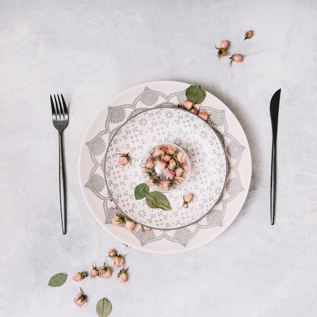 Kostenloses Foto teller mit blumen zwischen besteck