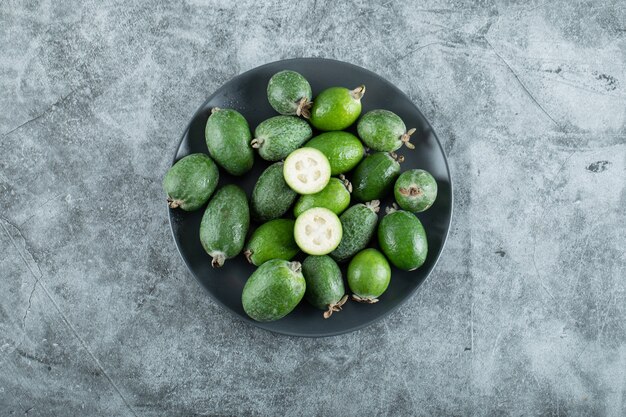 Teller mit Feijoa-Früchten auf Marmor.