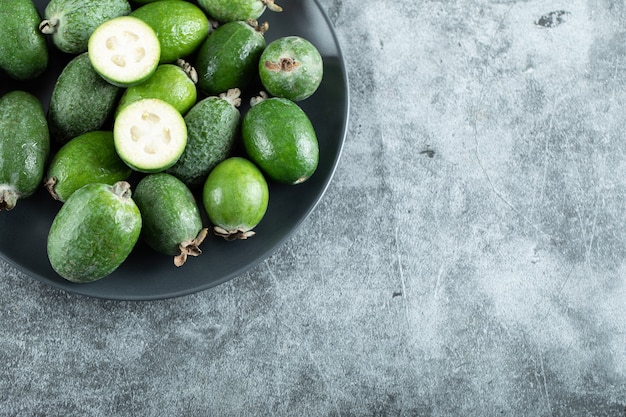 Teller mit Feijoa-Früchten auf Marmor.