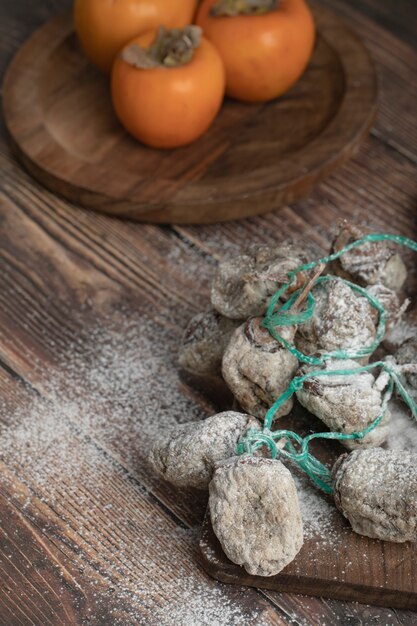 Kostenloses Foto teller mit frischem fuyu und getrockneten kakifrüchten auf holzbrett