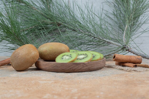 Teller mit frischen Kiwi- und Zimtstangen auf Marmortisch.