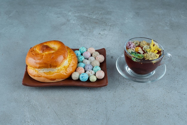 Teller mit Gebäck und Süßigkeiten mit einer Tasse Tee auf Marmor.