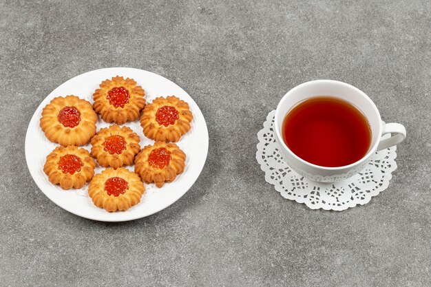 Teller mit geleekeksen und tasse tee auf marmoroberfläche