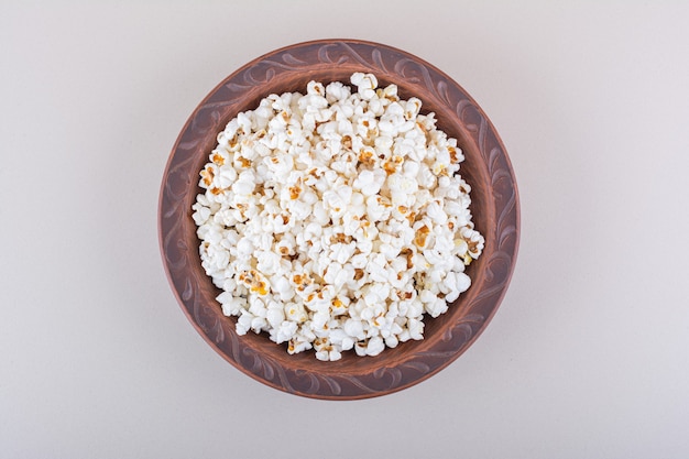 Teller mit gesalzenem Popcorn für Filmabend auf weißem Hintergrund. Foto in hoher Qualität