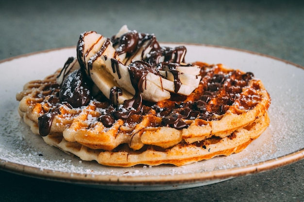 Kostenloses Foto teller mit gourmet-waffeln mit schokoladen- und bananenscheiben