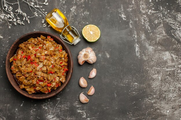 Teller mit grünen Bohnen Zitrone Knoblauch Flasche Öl Teller mit grünen Bohnen mit Tomaten auf dem schwarzen Tisch