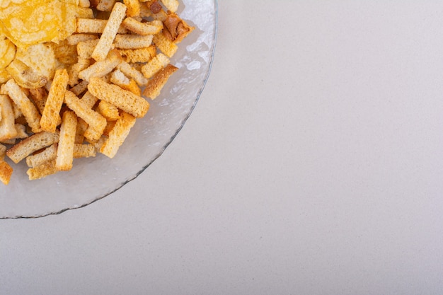 Kostenloses Foto teller mit leckeren knusprigen crackern und chips auf weißem hintergrund. foto in hoher qualität