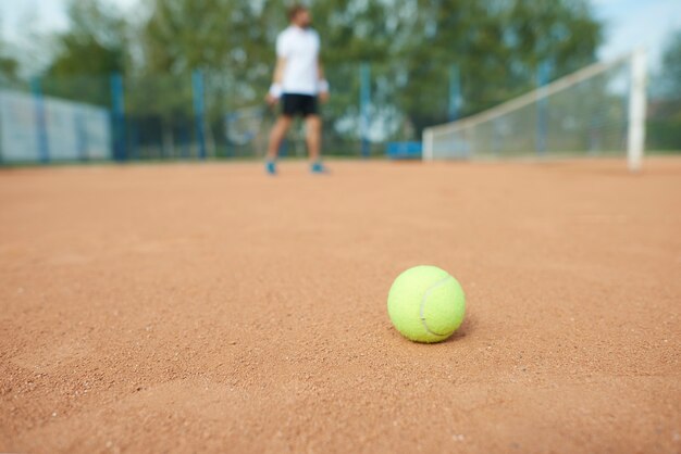 Tennisball und Mann auf dem Tennisplatz