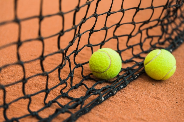 Tennisball zwei nahe dem schwarzen Netz auf dem Boden