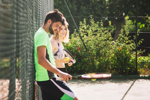 Tennisfreunde, die an Zaun lehnten