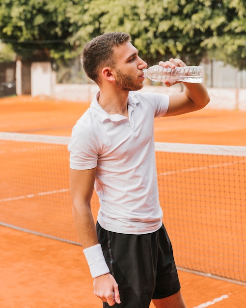 Tennisspieler, der etwas Wasser trinkt