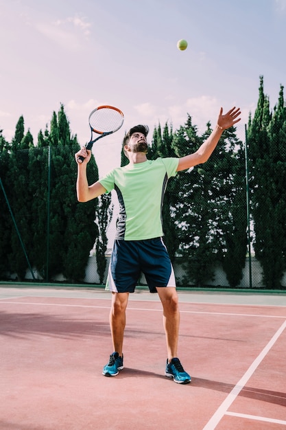 Tennisspieler im grünen T-Shirt serviert