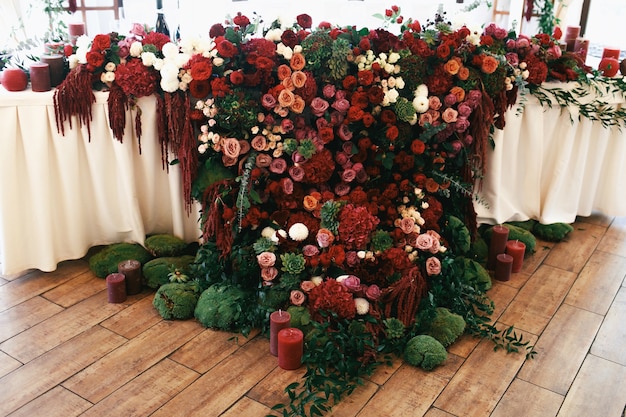 Teppich von roten Blumen und Moos hängt vom Abendtisch