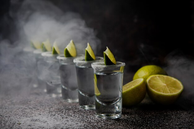 Tequila von der Seite in einem Glas, serviert mit Limetten und Salz