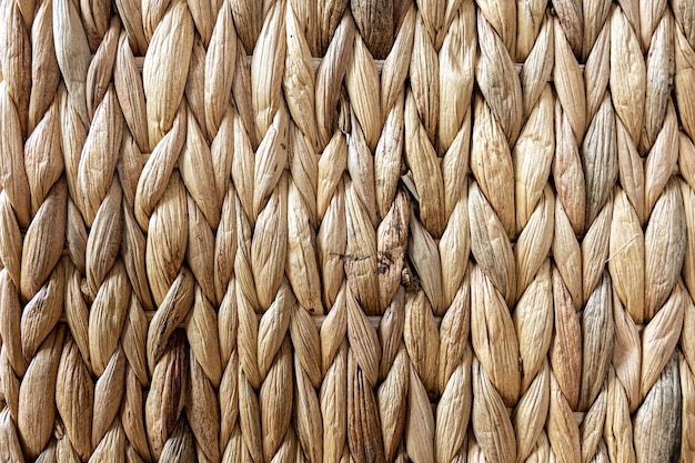 Textur aus gewebtem beigefarbenem Stroh, Hintergrund von Zöpfen aus der Nahaufnahme des Pflanzenstamms.