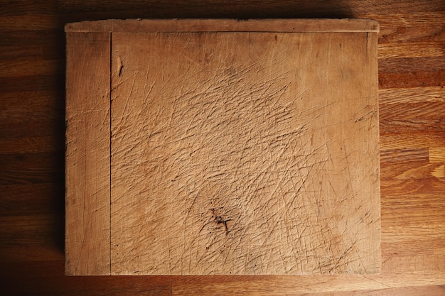 Textur eines sehr alten und stark genutzten Schneidebretts mit tiefen Schnitten auf einem schönen braunen Holztisch