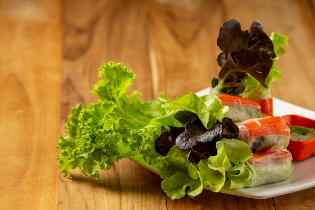 Thai-Salatbrötchen mit würzigem Knoblauch-Dip auf einem Holzboden.