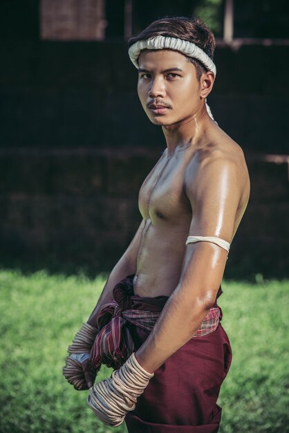 Thailändische Boxer wickeln das Klebeband in die Hände und stehen auf dem Rasen.