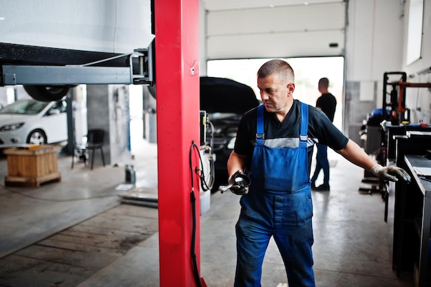 Thema Autoreparatur und -wartung Mechaniker in Uniform, der im Autoservice arbeitet