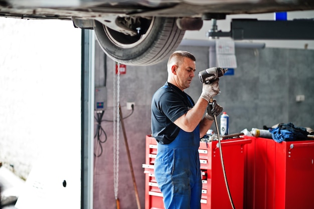 Thema Autoreparatur und -wartung Mechaniker in Uniform, der im Autoservice arbeitet