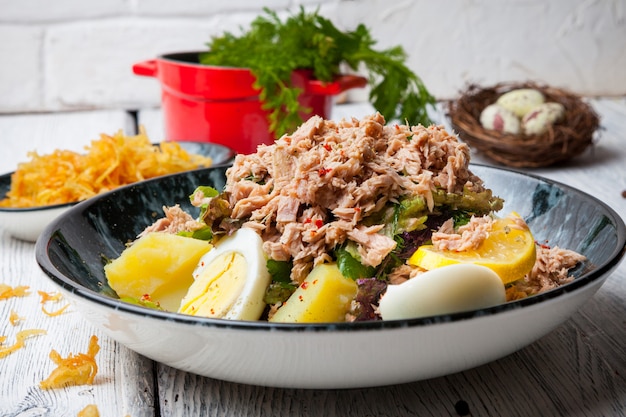 Thunfischsalat von der Seite in der Platte mit Eiern, Kartoffeln und Eiern auf Holztisch