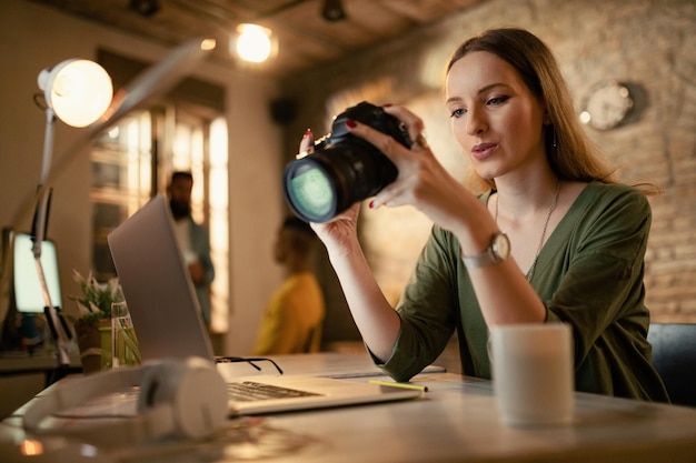 Tiefwinkelansicht einer Fotografin, die sich Fotos vor der Kamera ansieht, während sie spät im Büro arbeitet