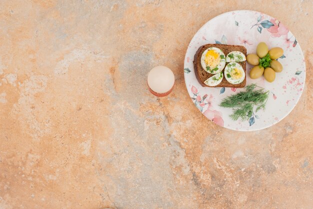 Toast mit gekochten Eiern, Oliven auf weißem Teller