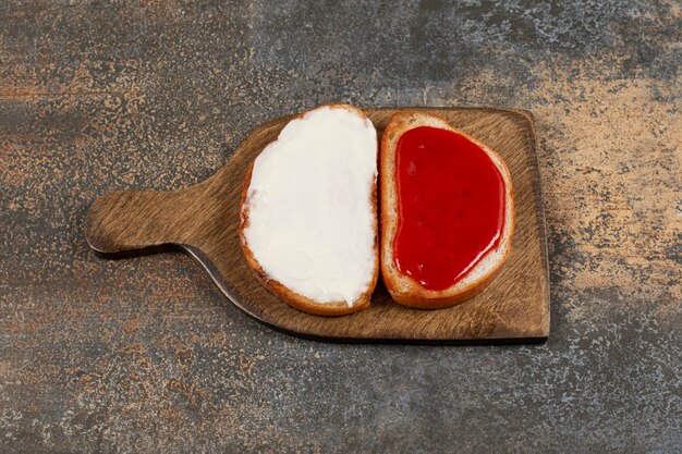 Toast mit Marmelade und Sauerrahm auf Holzbrett.