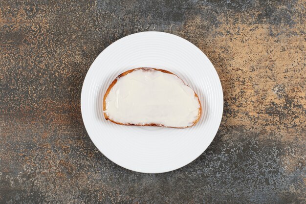 Toastscheibe mit saurer Sahne auf weißem Teller.
