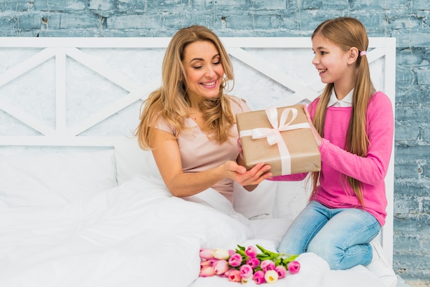 Kostenloses Foto tochter, die der mutter im bett geschenkbox gibt