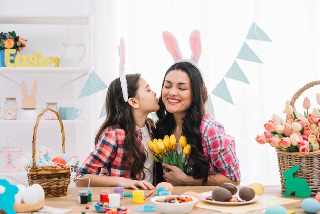 Tochter, die ihre Mutter auf Ostern-Tagesfeier küsst