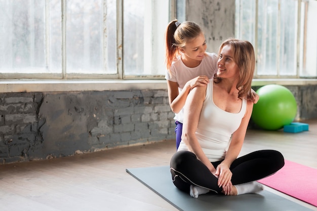 Tochter, die Mutter umarmt, die Yoga-Pose tut