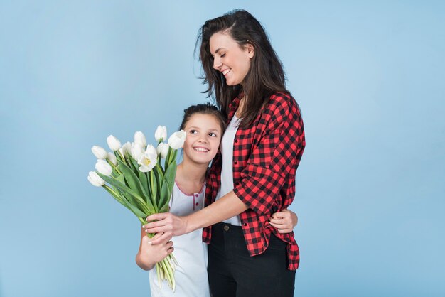 Tochter, die Mutter umarmt und ihren Tulpen gibt