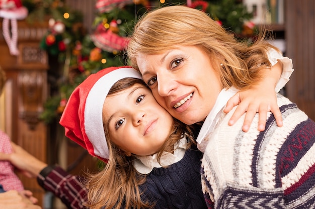 Tochter mit Weihnachtsmütze umarmt ihre Mutter