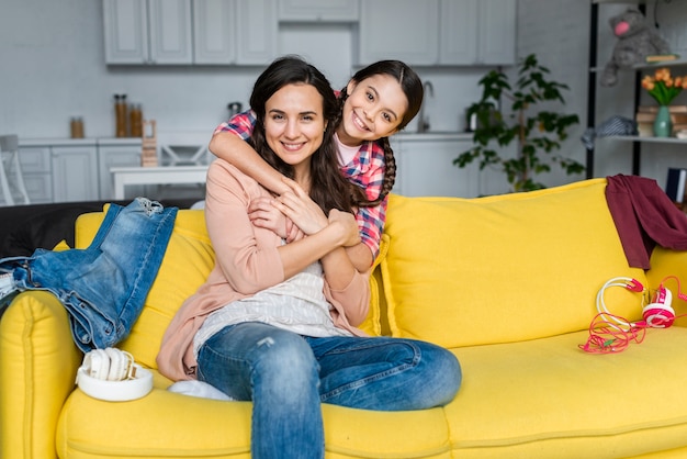 Tochter umarmt ihre Mutter auf dem Sofa