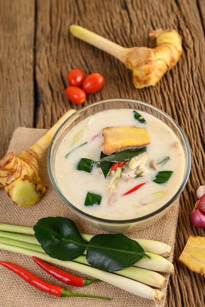 Tom Kha Kai in einer Schüssel mit Kaffirlimettenblättern, Zitronengras, roten Zwiebeln, Galangal und Chili.