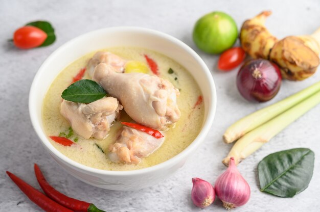 Tom Kha Kai in einer Schüssel mit Kaffirlimettenblättern, Zitronengras, roten Zwiebeln, Galangal und Chili.