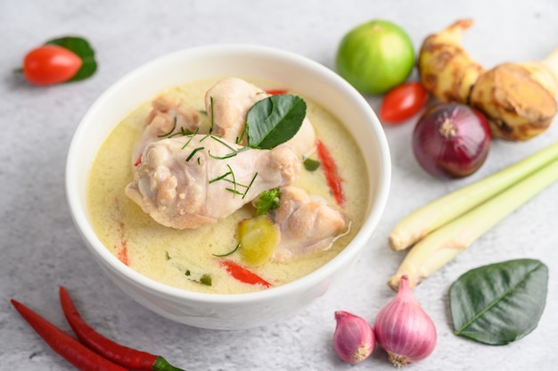 Tom Kha Kai in einer Schüssel mit Kaffirlimettenblättern, Zitronengras, roten Zwiebeln, Galangal und Chili.