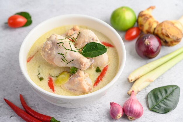 Tom Kha Kai in einer Schüssel mit Kaffirlimettenblättern, Zitronengras, roten Zwiebeln, Galangal und Chili.