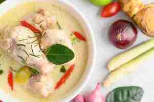 Kostenloses Foto tom kha kai in einer schüssel mit kaffirlimettenblättern, zitronengras, roten zwiebeln, galangal und chili.