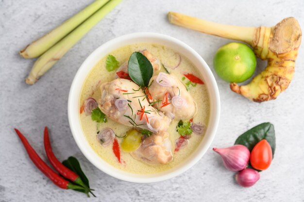 Tom Kha Kai in einer Schüssel mit Kaffirlimettenblättern, Zitronengras, roten Zwiebeln, Galangal und Chili.