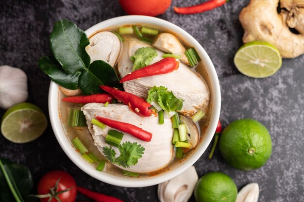 Tom Yum Huhn mit Chili, Koriander, getrocknetem Chili, Kaffirlimettenblättern, Pilzen und Zitronengras in einer Schüssel