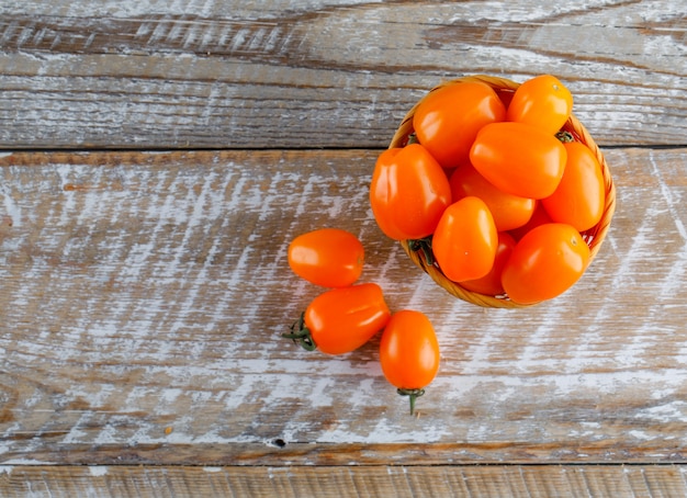 Tomaten in einem Korb auf einem Holztisch. flach liegen.