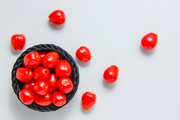 Tomaten in einer Schüssel und auf einer weißen Oberfläche. Draufsicht.