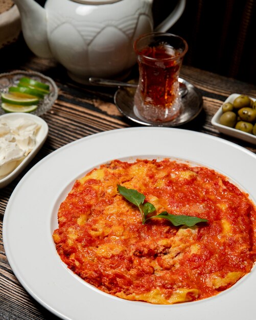 Tomaten mit Eiern und einer Tasse heißen Tee