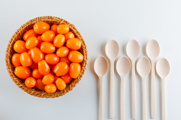 Tomaten mit Holzlöffeln in einem Weidenkorb, flach gelegt.