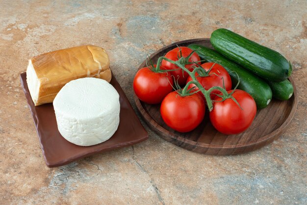 Tomaten und Gurken mit Käse auf Marmortisch.