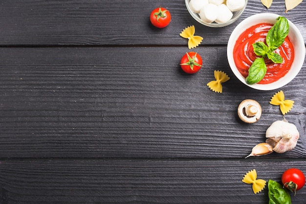 Tomatensauce mit Bestandteilen auf schwarzer hölzerner Planke