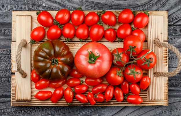 Tomatensorte in einem rustikalen handgemachten Tablett auf einer grauen Holzwand. flach liegen.