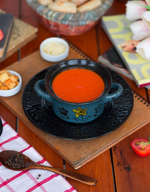 Tomatensuppe in einem Topf mit gehacktem Parmesankäseparmesan und Brotcrackern.